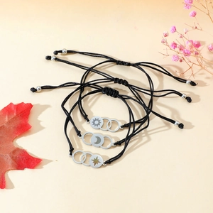 Detailed view of adjustable sun moon and star charms on black braided bracelets