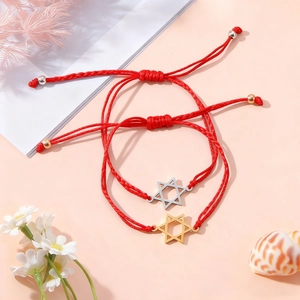Detail von zwei roten geflochtenen Armbändern mit Davidstern-Anhängern auf Muscheln