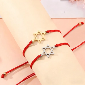Detailansicht der roten geflochtenen Armbänder mit Gold- und Silbersternanhängern