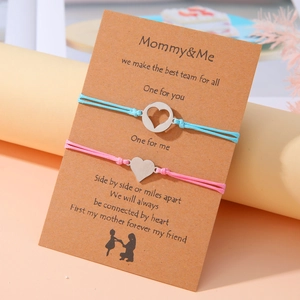 Detalle de pulseras tejidas para madre e hija con dijes de corazón en tarjeta