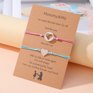 Detalle de pulseras Mommy & Me con dijes de corazón sobre una tarjeta de regalo suave