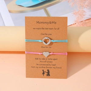 Detalle de las pulseras para madre e hija con colgantes de corazón en tarjeta de regalo