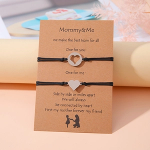Detalle de las pulseras Mommy & Me con dijes de corazón en tarjeta de regalo kraft
