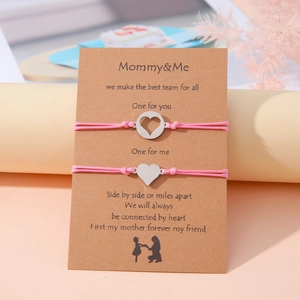 Detalle de dos pulseras de cordón rosa con corazones sobre tarjeta de regalo de papel kraft
