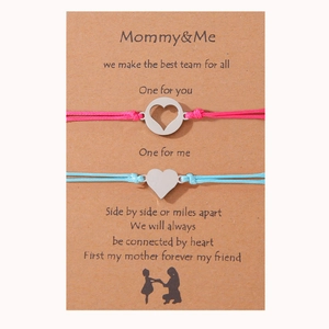 Detalle de las pulseras trenzadas Mommy & Me con corazón sobre tarjeta de regalo y silueta