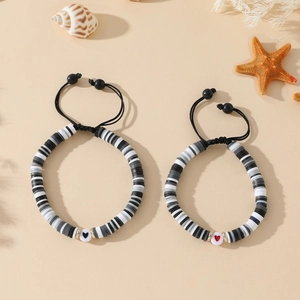 Détail de bracelets ajustables en perles d'argile noir blanc gris avec motifs cœur