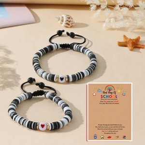 Détail de deux bracelets faits main avec perles Heishi et cœurs sur carte cadeau d'école