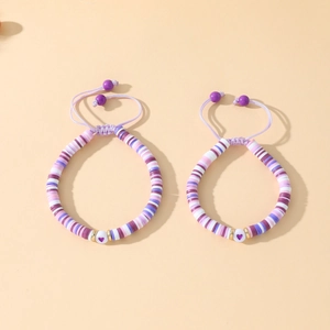 Détail de bracelets réglables en perles heishi coeur violet et blanc avec cordon