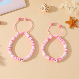Détail de deux bracelets Heishi roses réglables avec breloques cœur et décors de coquillages