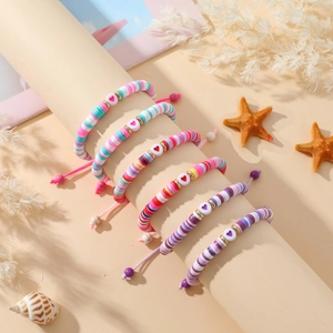 Détail de bracelets bohèmes en perles d'argile colorées avec breloques cœur et étoile