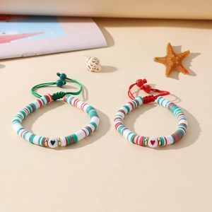 Détail de deux bracelets en perles d'argile colorées avec breloques cœur et cordons