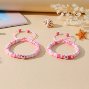 Détail de bracelets heishi à perles de cœur rose avec cordon réglable sur sable