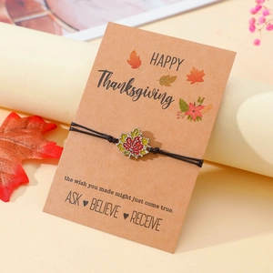Details des schwarzen Kordelarmbands mit Ahornblatt-Anhänger auf Thanksgiving-Karte