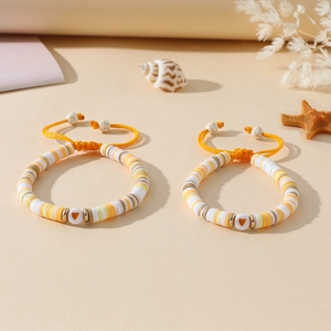 Détail macro de deux bracelets réglables en argile avec perles cœur jaune et blanc