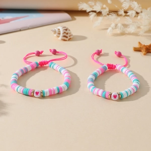Détail de bracelets faits main en perles heishi avec cœurs et cordons roses réglables en nylon