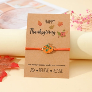 Detail eines gewebten Kürbisarmbands mit Happy Thanksgiving Geschenkkarte und Ahornblatt