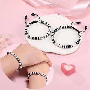 Détail de bracelets cœur réglables noir et blanc posés sur une plaque décorative en céramique