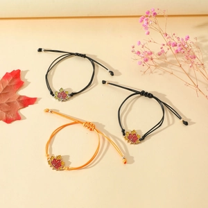 Makroaufnahme von drei handgewebten Armbändern mit Ahornblatt-Anhänger und goldenen Perlen