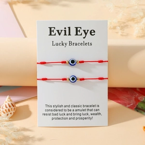 Détail de deux bracelets œil maléfique rouges sur carte avec coquillages et fleurs séchées
