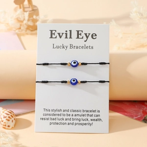 Détail de deux bracelets porte-bonheur Evil Eye tressés noirs sur carte de présentation