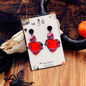 Λεπτομέρεια από σκουλαρίκια Halloween με ροζ νεκροκεφαλή και κόκκινη καρδιά σε κάρτα