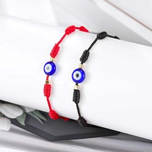 Détail de bracelets Evil Eye tressés rouges et noirs avec perles dorées sur support