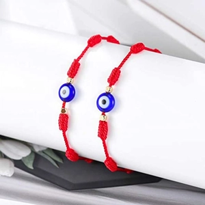 Gros plan sur des bracelets d'amitié tressés rouges avec perles œil bleu et détails dorés