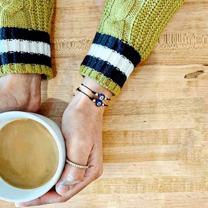 Détail de bracelets d'amitié noirs avec des perles mauvais œil bleu sur une tasse à café