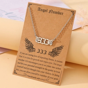 Macro detail of silver angel number 333 necklace with wings on a handmade display card