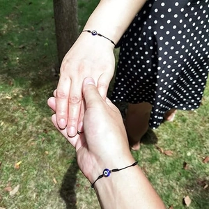 Gros plan de deux amis portant des bracelets réglables Evil Eye en cordon noir en extérieur
