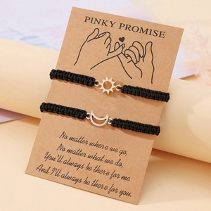 Dettaglio di braccialetti intrecciati con sole e luna su carta Pinky Promise