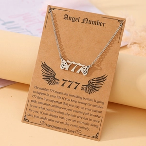 Macro detail of silver 777 angel number necklace with wings on kraft card display