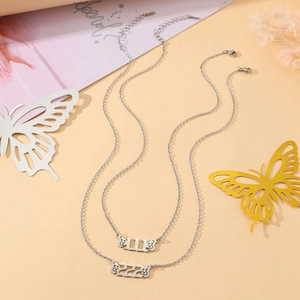 Detail of stainless steel angel wing necklaces featuring 111 and 222 numerical pendants