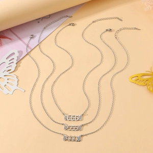 Detailed view of silver angel wing necklaces with numbers 111, 444, and 555 set on beige decor