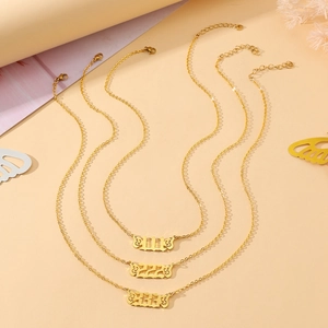 Detail of gold angel wing necklaces featuring carved numbers 111, 222, and 333