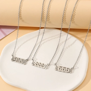 Detailed view of silver angel wing year necklaces 1994, 2006, and 2010 on a ceramic tray