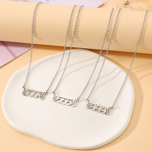 Detailed view of silver angel wing necklaces with numbers 777 555 and 444 on a ceramic plate