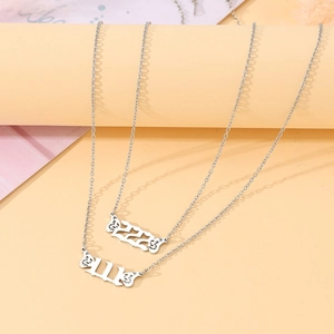 Close-up of silver 111 and 222 angel number necklaces with butterfly wings details