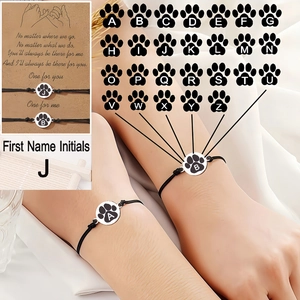 Détail de bracelets d'amitié tressés avec pendentif patte de chat et initiale
