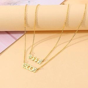 Detailed shot of gold butterfly wing necklaces featuring engraved numbers 444 and 333