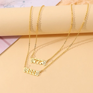 Close-up of gold stainless steel necklaces featuring 777 and 888 angel wing pendants