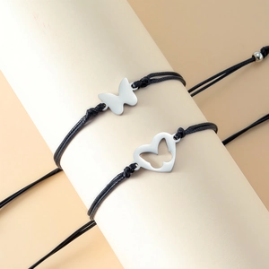 Close-up of adjustable black woven bracelets with stainless steel butterfly heart pendants