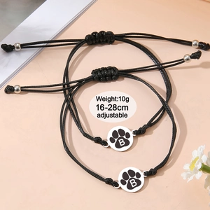 Détail de bracelets de couple tressés noirs réglables avec breloques patte de chat argent
