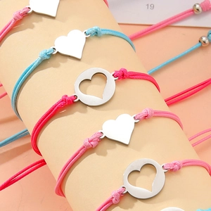 Detail von bunten geflochtenen Armbändern mit herzförmigen Anhängern aus Edelstahl