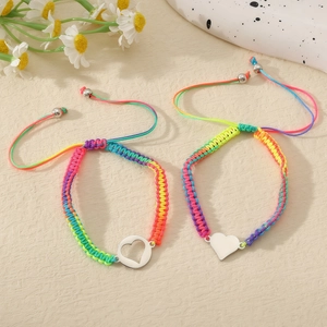 Detail von Regenbogen Armbändern mit Herzanhängern auf strukturierter Fläche