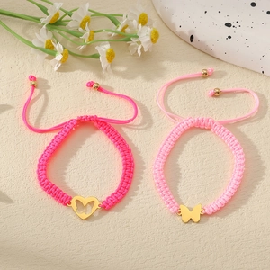 Detail der handgewebten Herz- und Schmetterlingsarmbänder in Rosa mit verstellbarem Golddekor