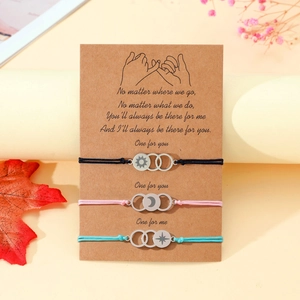 Detailed close-up of sun, moon and star charms on braided friendship bracelets with card
