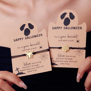 Close-up of Halloween spider and web pendants on black woven bracelets with ghost card