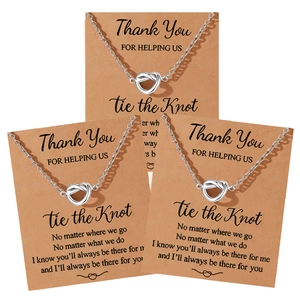 Detalle de tres collares con nudo de corazón en tarjetas de regalo kraft para bodas