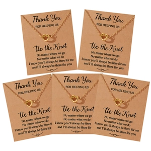 Detalle de cinco collares de corazón dorados en tarjetas kraft para damas de honor